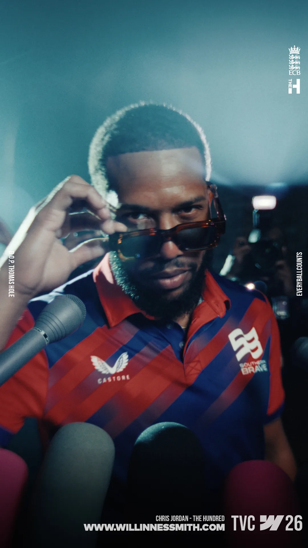 Chris Jordan lowering his sunglasses in front of a press scrum · The Hundred
